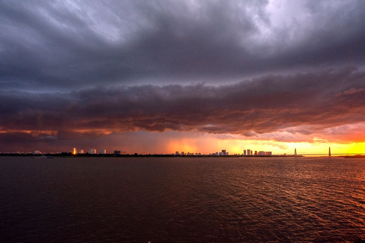 A city skyline under a dramatic stormy sky with a vibrant sunset provides a powerful contrast.